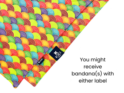 Close-up of two colorful pet bandanas with traditional Japanese wave patterns in bright rainbow colors. The bandanas feature two different labels: one with a KIKI Japan logo, and another with a simple KIKI text logo. Text reads: "You might receive bandana(s) with either label."